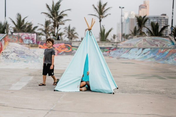 Kids playing in blue teepee play tent at skatepark